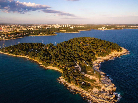 Aerial view of Camping Arena Stoja, a lush green peninsula in Istria, Croatia, bordered by blue sea.
