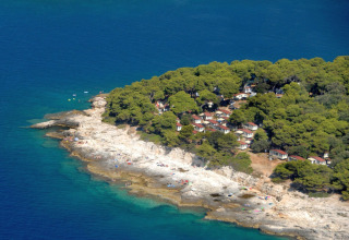 Vista aérea de Camping Arena Stoja en Istria, Croacia, con casas rodeadas de pinos y costa rocosa junto al mar.