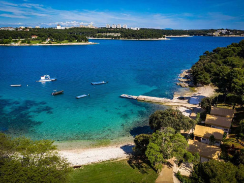 Vista aerea di Camping Arena Stoja in Istria, Croazia, con mare blu, barche e costa alberata.