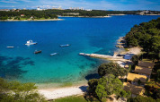 Aerial view of Camping Arena Stoja in Istria, Croatia, with crystal blue sea, boats, rocky coast and trees.