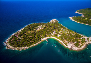 Aerial view of Camping Arena Stoja holiday park on a lush peninsula surrounded by clear sea in Istria, Croatia.