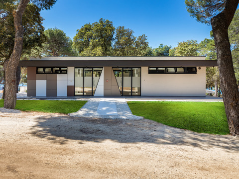Modern sanitairgebouw omringd door pijnbomen bij Camping Arena Stoja vakantiepark in Istrië, Kroatië.