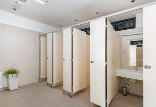 Baño moderno y limpio en Camping Arena Stoja, Istria, Croacia, con cabinas privadas y lavabo.