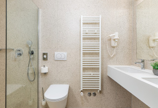 Bagno moderno con doccia, wc sospeso, scaldasalviette e doppio lavabo in un villaggio turistico.