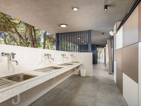 Modern outdoor washing area with multiple sinks at Camping Arena Stoja, Istria, Croatia, surrounded by trees.