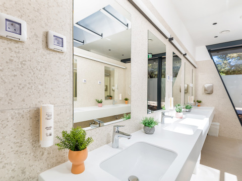 Bagno moderno e luminoso con lavandini, specchi e piante al Camping Arena Stoja, parco vacanze in Istria, Croazia.