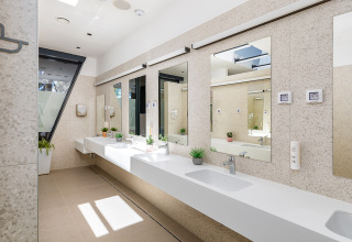 Bagno moderno e luminoso al Camping Arena Stoja in Istria, Croazia, con grandi specchi e piante decorative.
