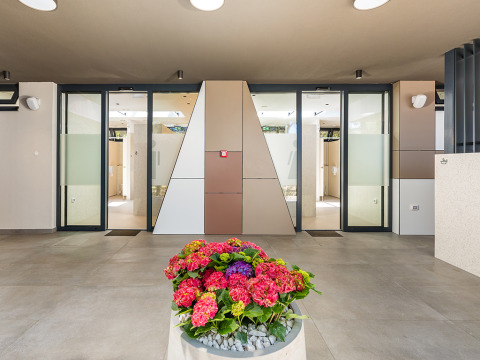 Ingresso ai servizi moderni con porte in vetro e fiori decorativi presso Camping Arena Stoja, Istria, Croazia.