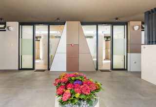 Ingresso ai servizi moderni con porte in vetro e fiori decorativi presso Camping Arena Stoja, Istria, Croazia.