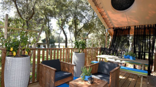 Buitenlounge met houten meubilair en citroenbomen in een tweeslaapkamer glamping safari tent.