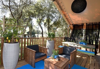 Area relax esterna con mobili in legno e piante di limoni in una tenda safari glamping con due camere.
