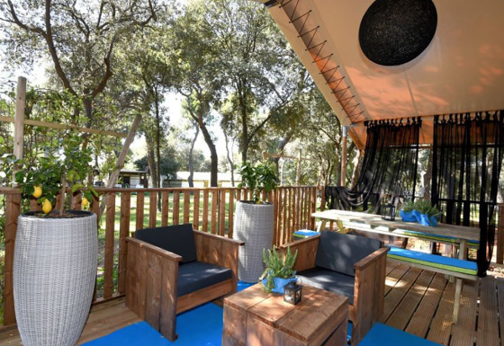 Outdoor-Lounge mit Holzmöbeln und Zitronenbäumen in einem zweizimmerigen Glamping-Safari-Zelt.