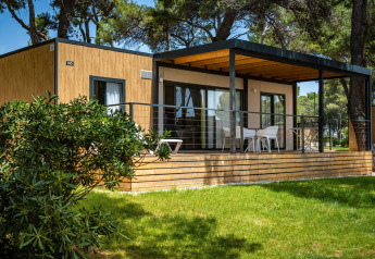 Lodge moderno en Camping Villa con fachada de madera, amplia terraza, zona de estar y naturaleza.