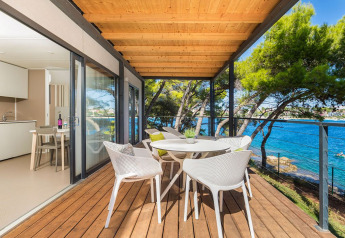 Overdekt houten terras met moderne stoelen en uitzicht op zee bij Camping Villa First Row, Arena Stoja.