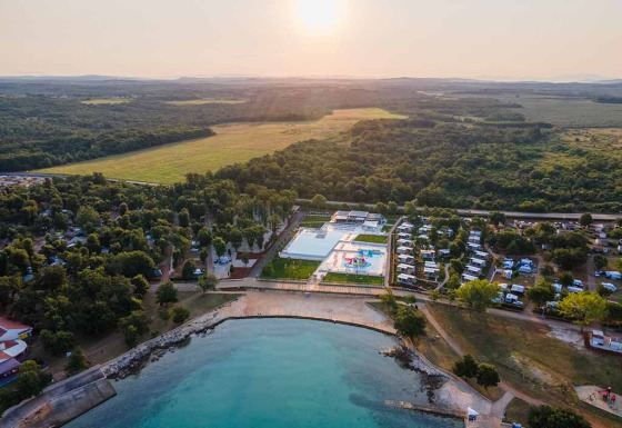 Vue aérienne de Camping Park Umag en Istrie, Croatie, avec piscine, verdure et plage au coucher du soleil.