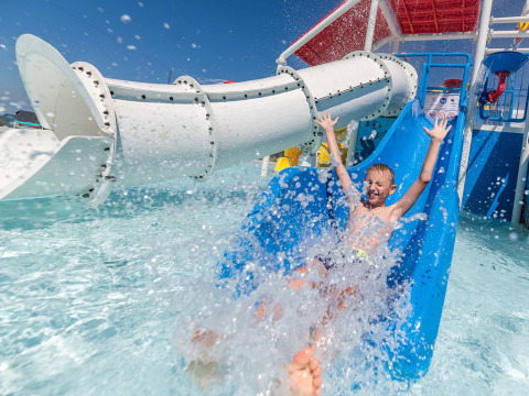Boy having fun on a water slide with splashing water at Camping Park Umag, a holiday park in Istria, Croatia.