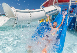 Garçon s'amusant sur un toboggan aquatique avec éclaboussures au Camping Park Umag, parc de vacances en Istrie, Croatie.
