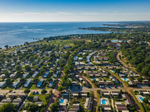 Vue aérienne du Camping Park Umag en Istrie, Croatie, avec des chalets, nature verdoyante et la mer.