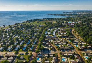 Aerial view of Camping Park Umag in Istria, Croatia, showing cabins, greenery, and a stunning coastline.