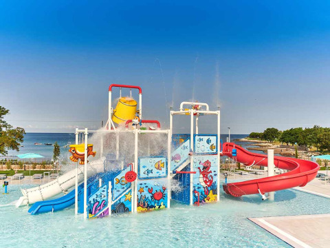 Wasserpark mit Rutschen und bunten Figuren im Camping Park Umag, Istrien, Kroatien, mit Meeresblick.