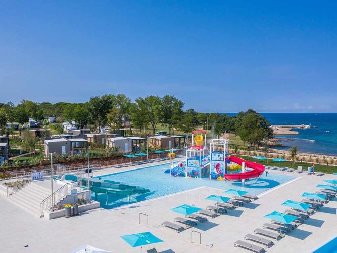 Vakantiepark Camping Park Umag in Istrië, Kroatië, met zwembad, glijbaan en uitzicht op zee en huisjes.