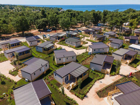 Aerial view of modern cabins at Camping Park Umag in Istria, Croatia, near the sea and surrounded by green trees.