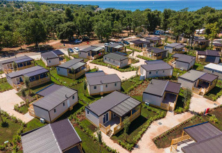 Vista aérea de cabañas modernas en Camping Park Umag, Istria, Croacia, junto al mar y rodeadas de árboles verdes.