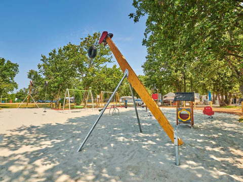 Parco giochi con altalene e attrezzature nel Camping Park Umag, Istria, Croazia, circondato da alberi.
