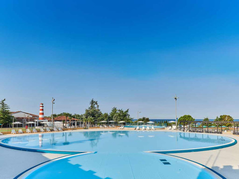 Camping Park Umag i Istrien, Kroatien, viser en stor swimmingpool med liggestole og parasoller i solskin.