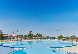 Camping Park Umag en Istria, Croacia, muestra una gran piscina exterior con tumbonas y sombrillas en día soleado.