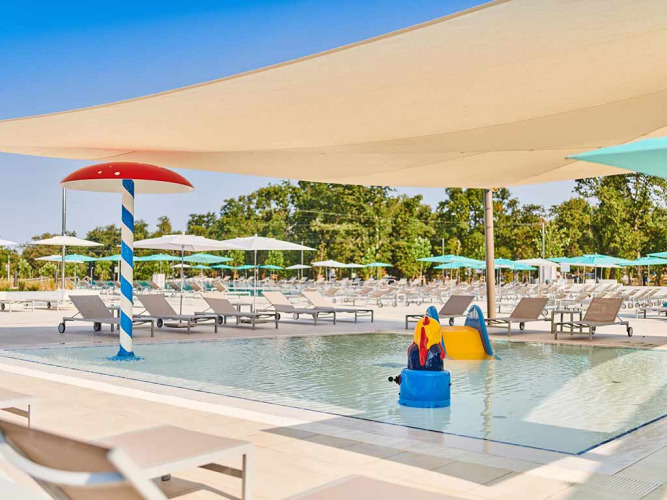 Kindvriendelijk zwembad met ligbedden, parasols en waterspeeltuin bij Camping Park Umag, Istrië, Kroatië.