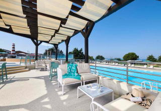 Outdoor lounge at Camping Park Umag in Istria, Croatia, featuring poolside sofas and shaded pergola.
