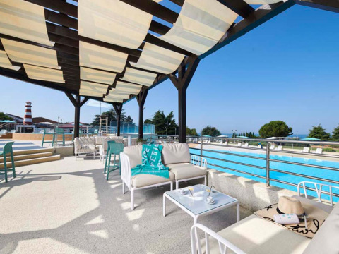 Outdoor lounge at Camping Park Umag in Istria, Croatia, featuring poolside sofas and shaded pergola.