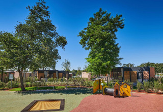 Speelplein met bomen en moderne chalets in Camping Park Umag, een vakantiepark in Istrië, Kroatië.