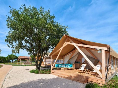 Glamping-Zelt mit Holzterrasse im Camping Park Umag, einer Ferienanlage in Istrien, Kroatien, bei klarem Himmel.
