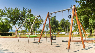 Legeplads med gynger og sand i Camping Park Umag, feriested i Istrien, Kroatien, omgivet af træer.