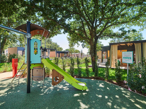 Parque infantil con tobogán bajo árboles en Camping Park Umag, un parque vacacional en Istria, Croacia.