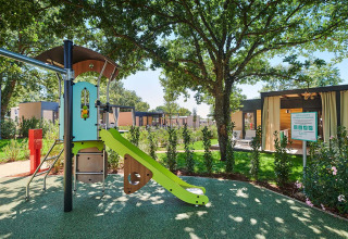 Parque infantil con tobogán bajo árboles en Camping Park Umag, un parque vacacional en Istria, Croacia.