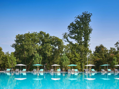 Piscina all'aperto con lettini e ombrelloni al Camping Park Umag, circondata da alberi in Istria, Croazia.