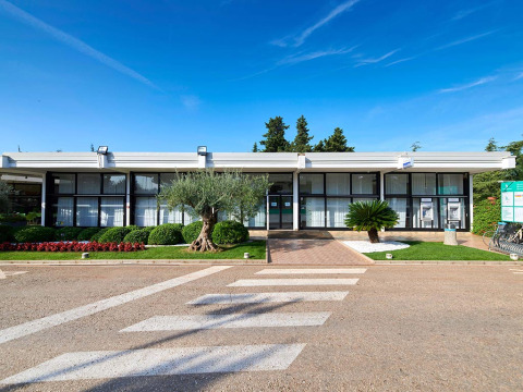 Main building with large windows at Camping Park Umag in Istria, Croatia, surrounded by neat gardens and sky.