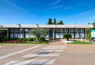 Main building with large windows at Camping Park Umag in Istria, Croatia, surrounded by neat gardens and sky.