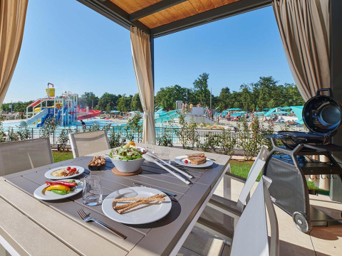 Tavolo da pranzo all'aperto con cibo al Camping Park Umag in Istria, Croazia, vista sul parco acquatico e piscina.