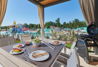 Tavolo da pranzo all'aperto con cibo al Camping Park Umag in Istria, Croazia, vista sul parco acquatico e piscina.