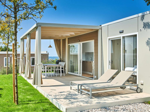 Moderne Ferienunterkunft mit Terrasse und Liegestühlen im Camping Park Umag, Istrien, Kroatien, an einem sonnigen Tag.