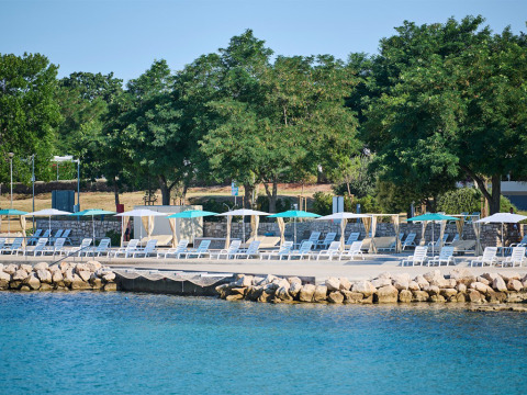 Sonnenliegen und Sonnenschirme an der Uferpromenade im Camping Park Umag, Istrien, Kroatien, am Wasser.