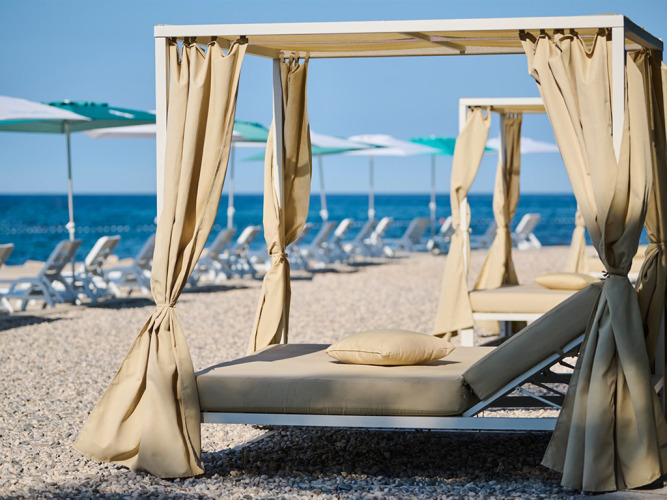 Luxe ligbedden met baldakijn op het kiezelstrand bij Camping Park Umag in Istrië, Kroatië.