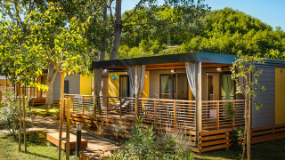 Moderna cabaña Lopar Garden Home con terraza de madera, rodeada de árboles y vegetación bajo el sol.