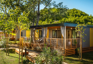 Moderne Lopar Garden Home lodge met houten terras, omgeven door groen en bomen in de zonneschijn.