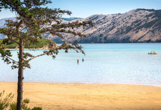 Sandstrand mit klar blauem Wasser und Bergen bei Valamar Camping San Marino, Kroatien.