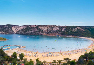Scenic sandy beach and bay with sunbathers and hills near Lopar, Primorje-Gorski Kotar, Croatia.